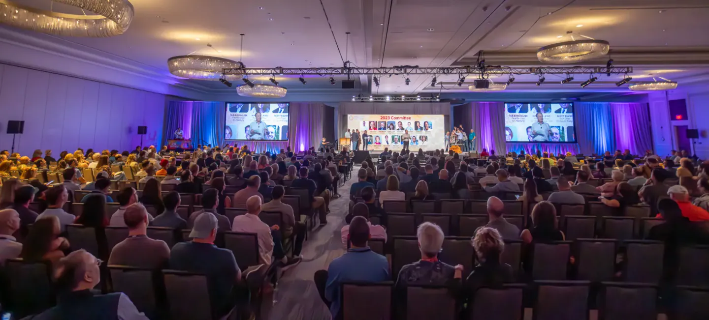 General session ballroom in Tampa, audience facing a stage and screens for the 2023 Committee