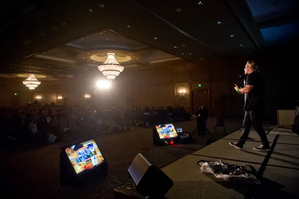 Speaker working the stage with confidence monitors at the deck edge