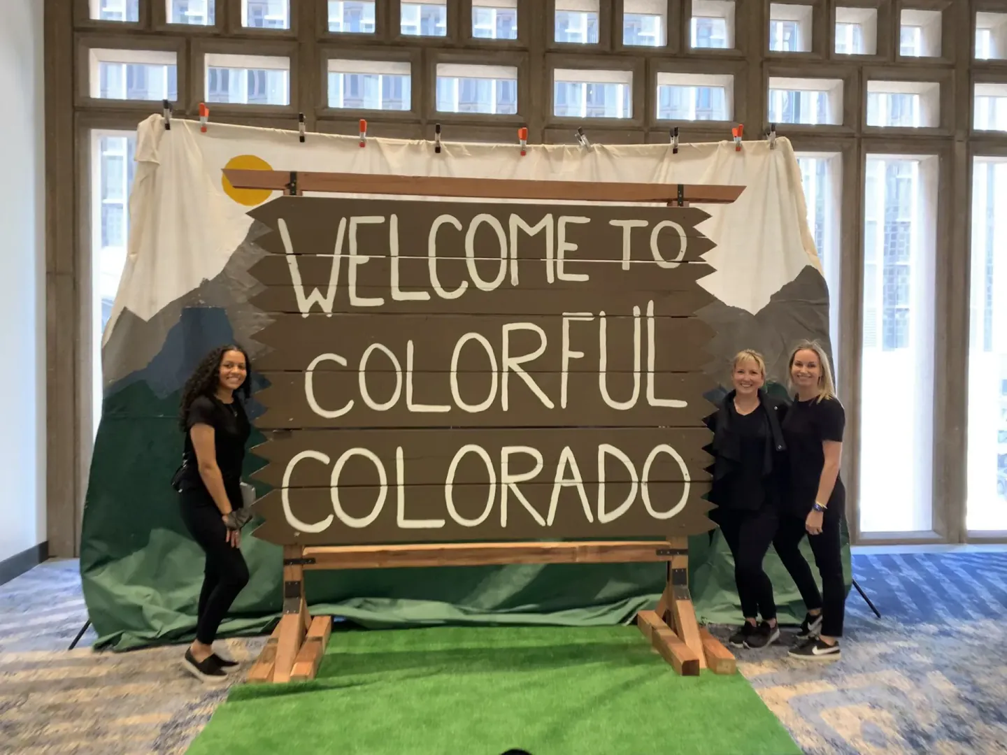 On-site staff with a Welcome to Colorful Colorado sign at the PAS 2022 meeting in Denver