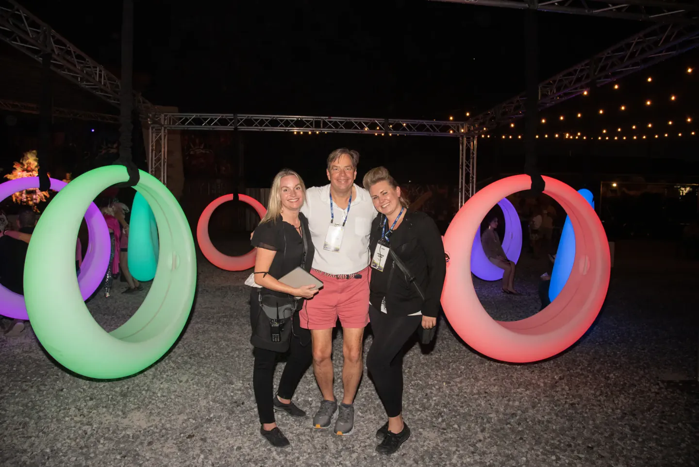 On-site staff with a guest among glowing swing rings at an evening event