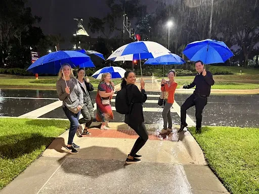 On-site team holding umbrellas in the rain at night