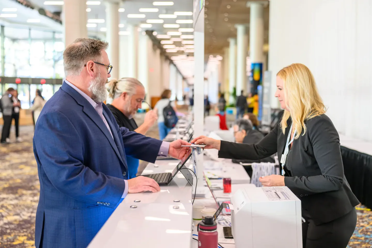 Staff handing a badge to an attendee at Trimble Insight, New Orleans, 2025